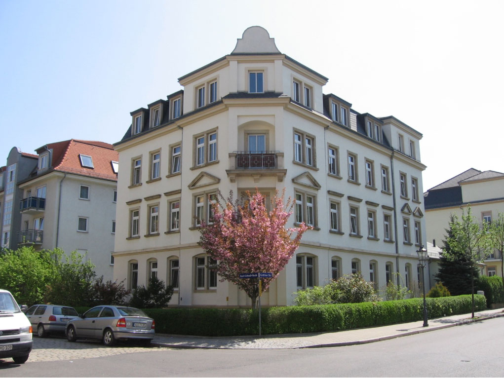 Auf dem Foto ist ein saniertes Wohnhaus auf der Emil-Überall-Str. zu sehen. Es ist ein helles Gründerzeitgebäude mit einer Buchsbaumhecke eingefaßt.