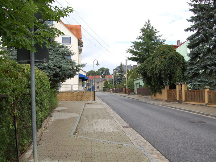 Das Foto zeigt den sanierten Fußweg und die neu asphaltierte Straße