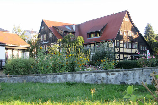 Das Bild zeigt das „Alte Fährgut“ in Loschwitz nach der Sanierung. Obstbäume und eine Steinmauer sieht man im Vordergrund.