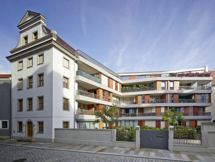 Neue Wohnanlage mit offener Hof zur Straße. Links historische Fassadenrekonstruktion. Balkone im Hof.
