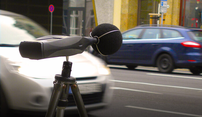 Ein Gerät zur Messung des Schallpegels steht an einer Straße
