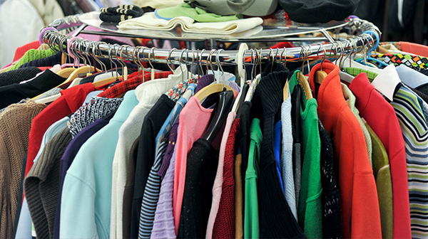 Hände in schwarzen Handschuhen halten ein aus Pappe ausgeschnittenes Haus