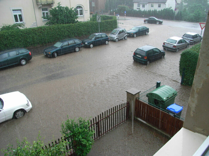Regenwasser macht eine Straße in einem Wohngebiet in Dresden zu einem Fluss.