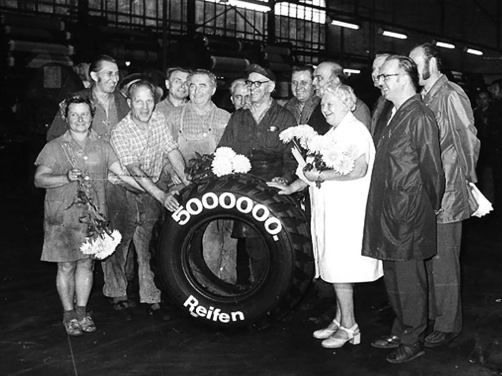 Personen posieren für ein Foto hinter einem großen LKW-Reifen