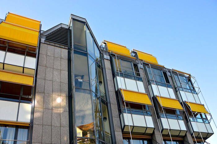 Foto eines Wohngebäudes mit gelben Markisen