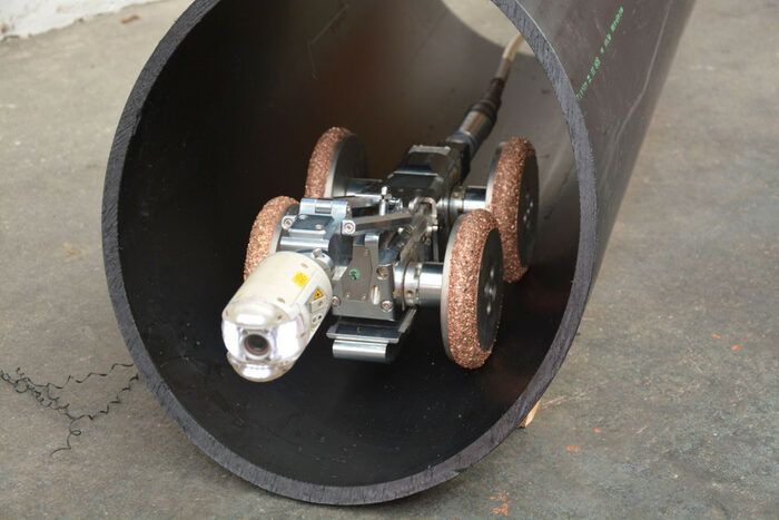 Foto von einem schwarze Rohr mit einer Sonde aus Metall zur Erkundung von Grundleitungen auf vier Rädern.