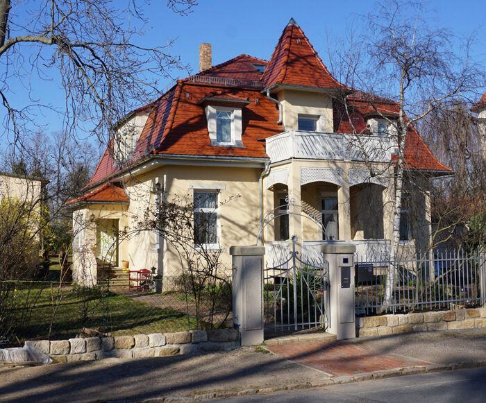 Freistehendes Einfamilienhaus mit rotem Dach und mehreren Gauben.