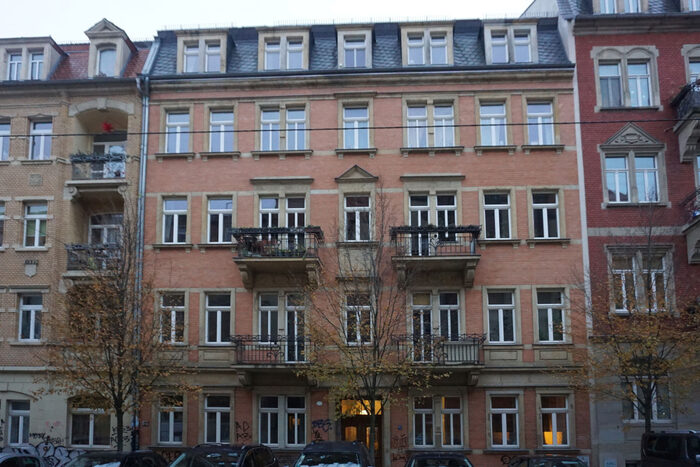 Viergeschossiges Reihenhaus mit roter Ziegelfassade und Balkonen.