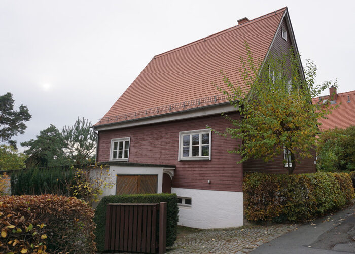 Zweigeschossiges Einfamilienhaus mit Holzfassade und rotem Satteldach.