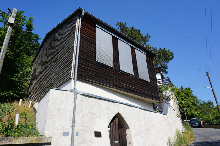Zweigeschossiges Einfamilienhaus mit dunkler Holzfassade und dunklem Satteldach.