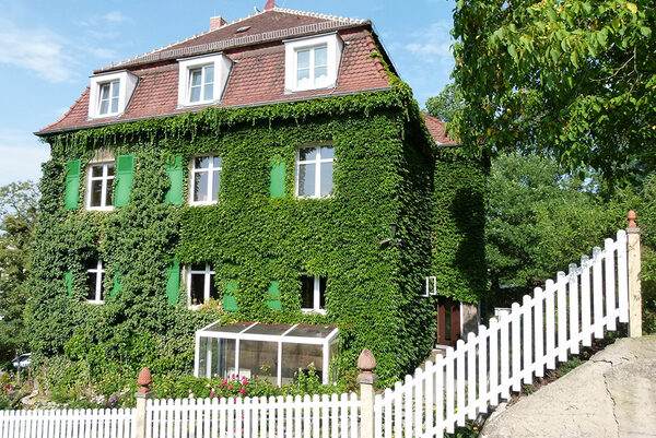 Mehrfamilienhaus mit grün bewachsener Fassade.