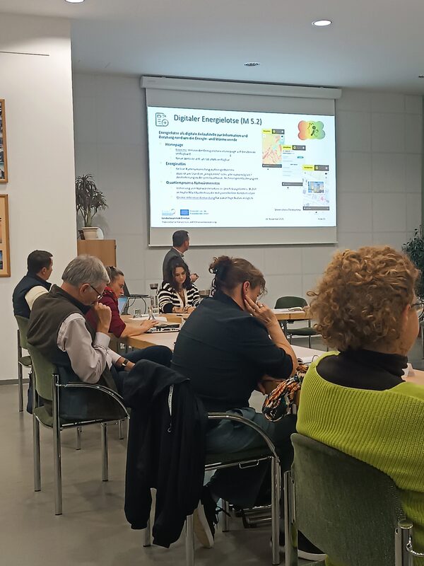 Während einer Sitzung des Stadtbezirksbeirats bzw. Ortschaftsrates wird die Kommunale Wärmeplanung der Landeshauptstadt Dresden vorgestellt. Mehrere Beiratsmitglieder sitzen an einem Tisch und verfolgen aufmerksam die Präsentation.