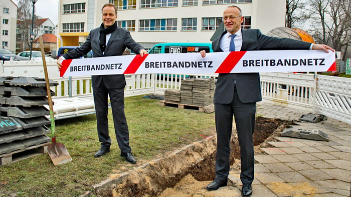 Dr. Frank Brinkmann (Geschäftsführer der DREWAG - Stadtwerke Dresden GmbH, links) und Bürgermeister Dr. Peter Lames (rechts) beim Start des Beritband-Ausbauprojektes Stadtnetz 500+. Sie halten ein Band in der Hand mit der Aufschrift "Breitbandnetz".