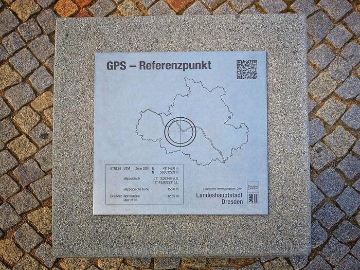 Foto der Platte auf dem Steinwürfel, auf der die Koordinaten des GPS-Referenzpunktes zu lesen sind.