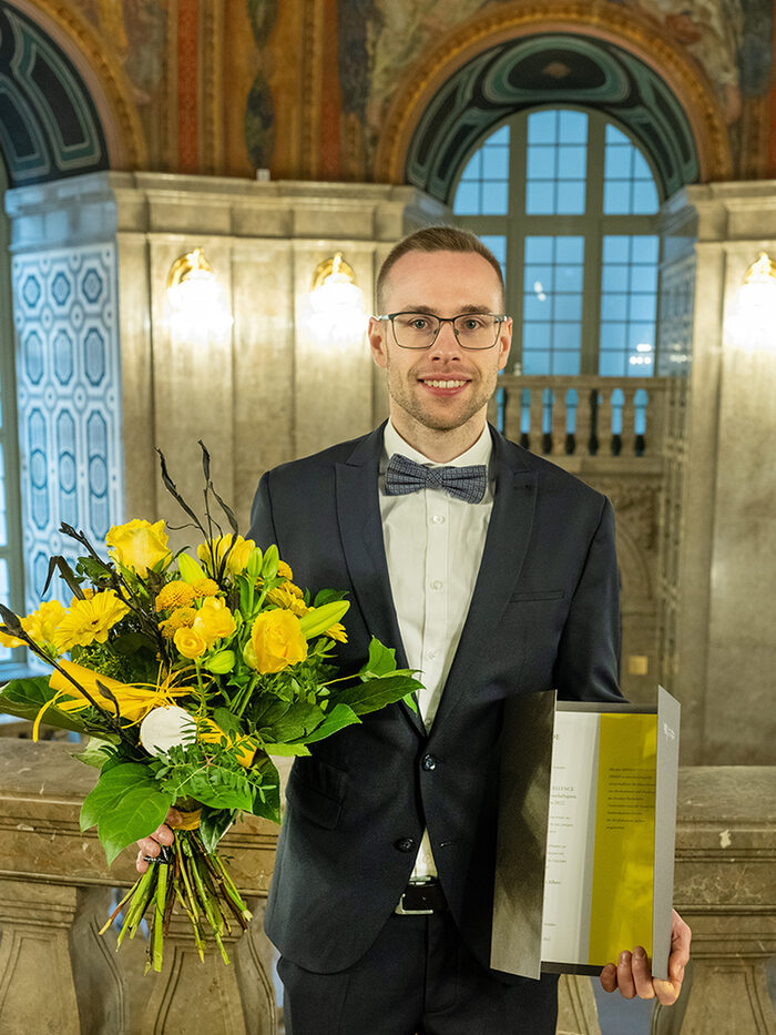 Carsten Albert, Preisträger Dresden Excellence Award 2022 Stufe Master/Diplom, mit Blumenstrauß und Urkunde