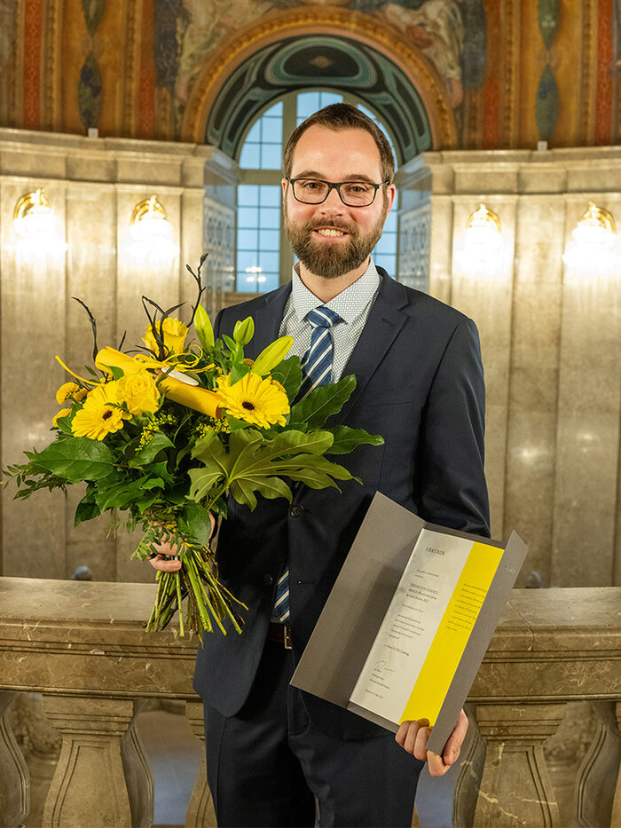 Dr. Felix Lansing, Preisträger Dresden Excellence Award 2022 Stufe Promotion, mit Blumenstrauß und Urkunde