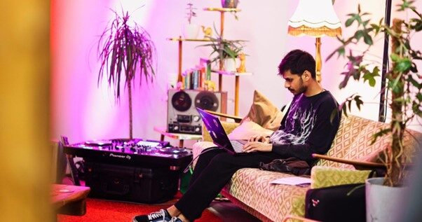 Mann sitzt mit Laptop auf einer Couch