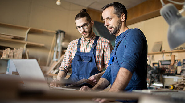 2 Männer arbeiten in einer Werkstatt an einem Laptop