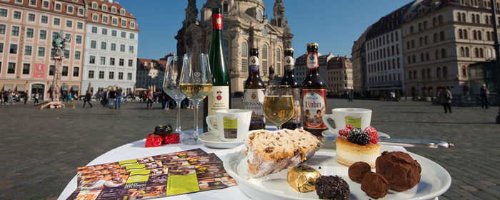Gedeckter Tisch mit sächsischen Spezialitäten wie Stollen, Eierschecke oder Radeberger Pilsner inmittem auf dem Neumarkt vor der Frauenkirche.