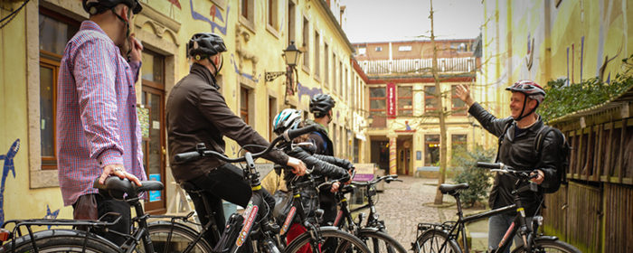Eine Gruppe Fahrradfahrer unterwegs mit einem Gästeführer in der Kunsthofpassage der Dresdner Neustadt.