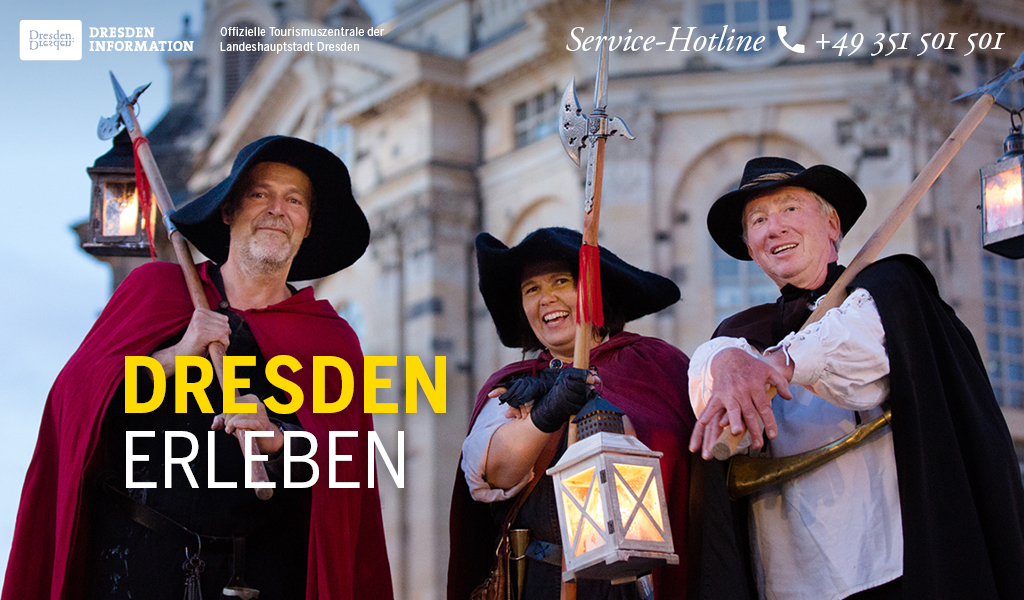 Drei Nachtwächter sind jeweils mit Hut, Umhang, Laterne und Hellebarde ausgestattet. Sie stehen direkt vor der Dresdner Frauenkirche und schauen lächelnd in die Kamera.