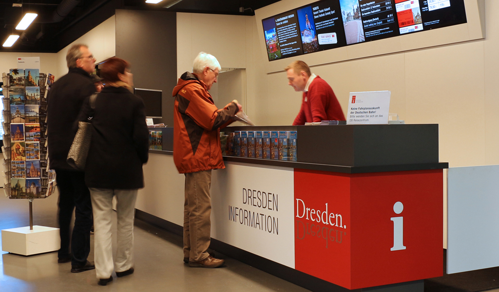 Besucher beim Buchen von einer Stadtbesichtigung in der Dresden Information im Hauptbahnhof