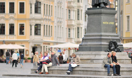 Gäste und Dresdner machen es sich auf dem Sockel der Martin-Luther-Statue gemütlich und beobachten das Treiben auf dem Neumarkt.