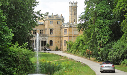 Blick auf das Schloss Eckberg, die umliegende Natur und den Springbrunnen mit Fontäne