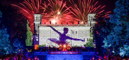 Feuerwerk über dem bunt beleuchteten Schloss Albrechtsberg. Auf der Fassade ist eine Ballerina abgebildet und darunter ein Banner mit dem Schriftzug Dresdner Schlössernacht.