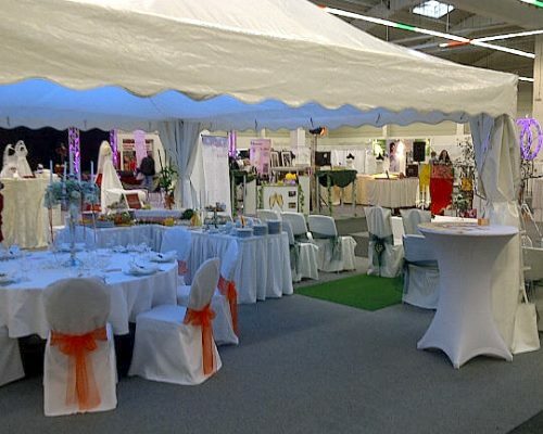 Hochzeitsdekoration für ein Zelt mit dekorierten Tischen und Stühlen, ausgestellt auf einer Messe.